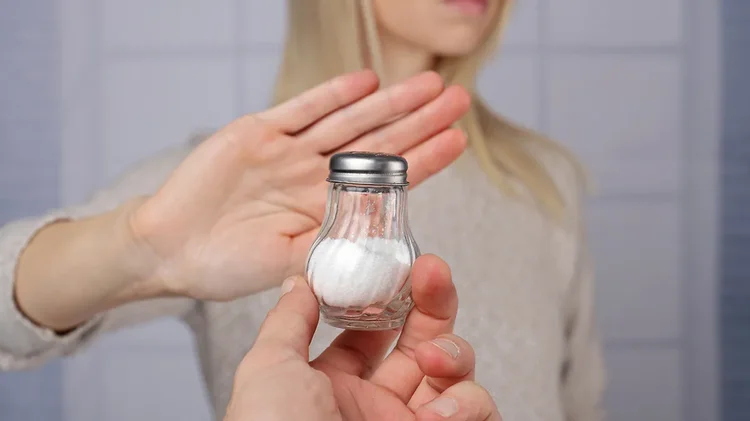 Person lehnt Salzstreuer ab, um Salzkonsum zu reduzieren.