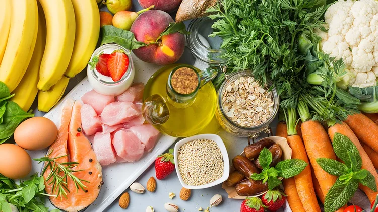 Tisch mit gesunden Lebensmitteln wie Fisch, Obst, Gemüse und Olivenöl.