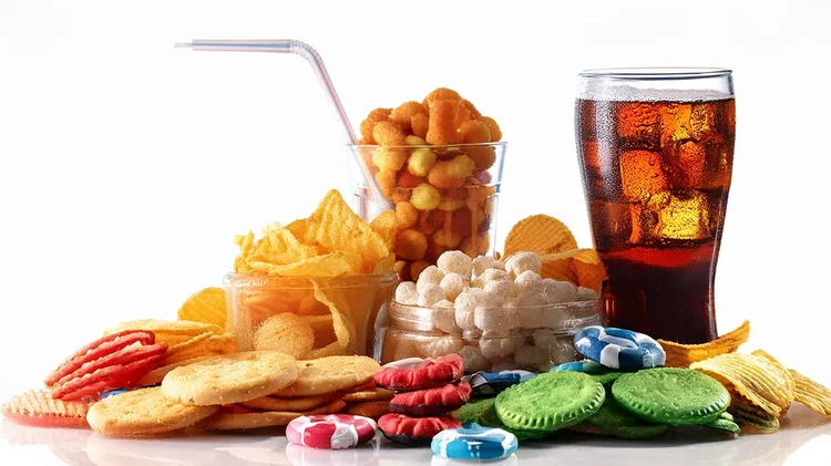 Chips, Süßigkeiten und Cola auf weißem Hintergrund.