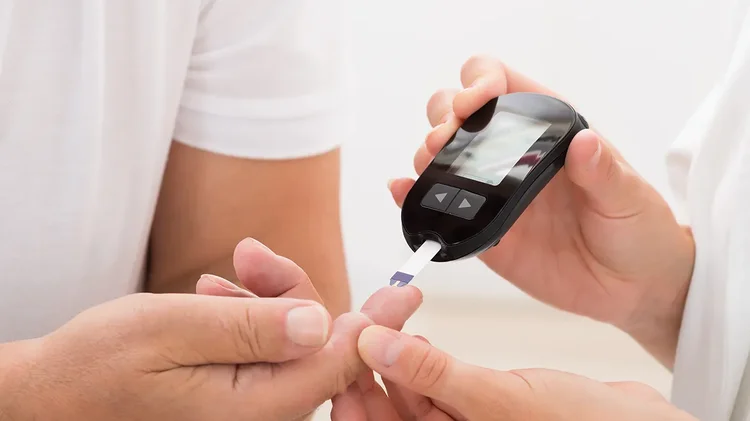 Person misst Blutzucker mit elektronischem Messgerät.