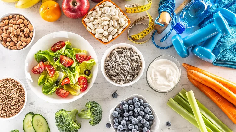 Gesunde Lebensmittel, Hanteln und Maßband auf Tisch als Symbol für ausgewogene Ernährung.