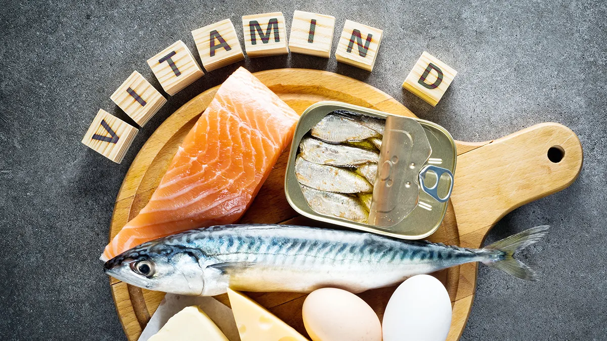 Vitamin-D-reiche Lebensmittel wie Fisch, Eier und Käse auf einem Holzbrett.