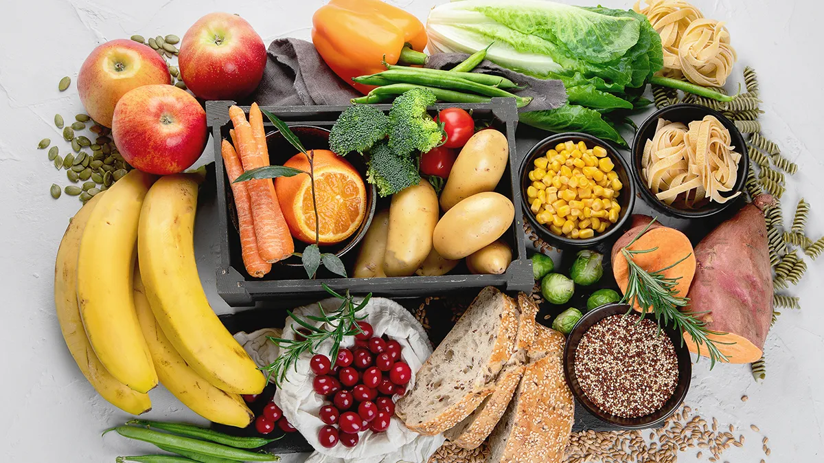 Vielfältiges Obst, Gemüse, Brot und Getreide auf einem hellen Untergrund.
