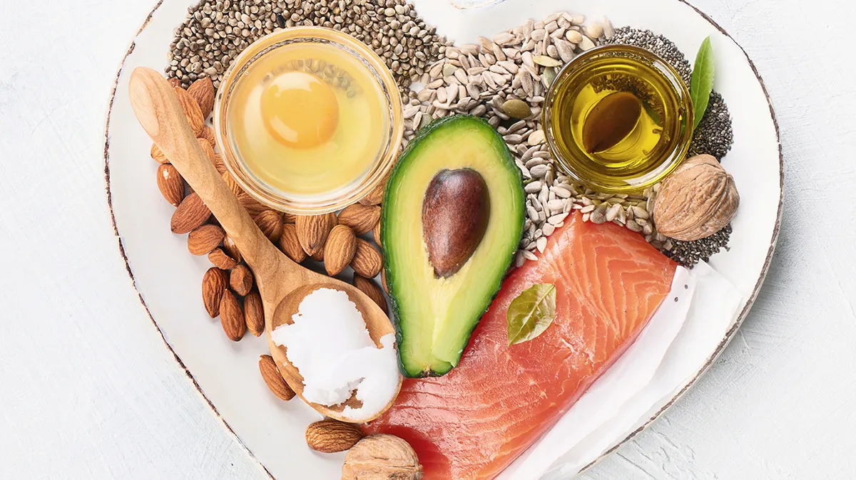 Avocado, Lachs, Nüsse, Samen und Ei auf einem herzförmigen Teller.