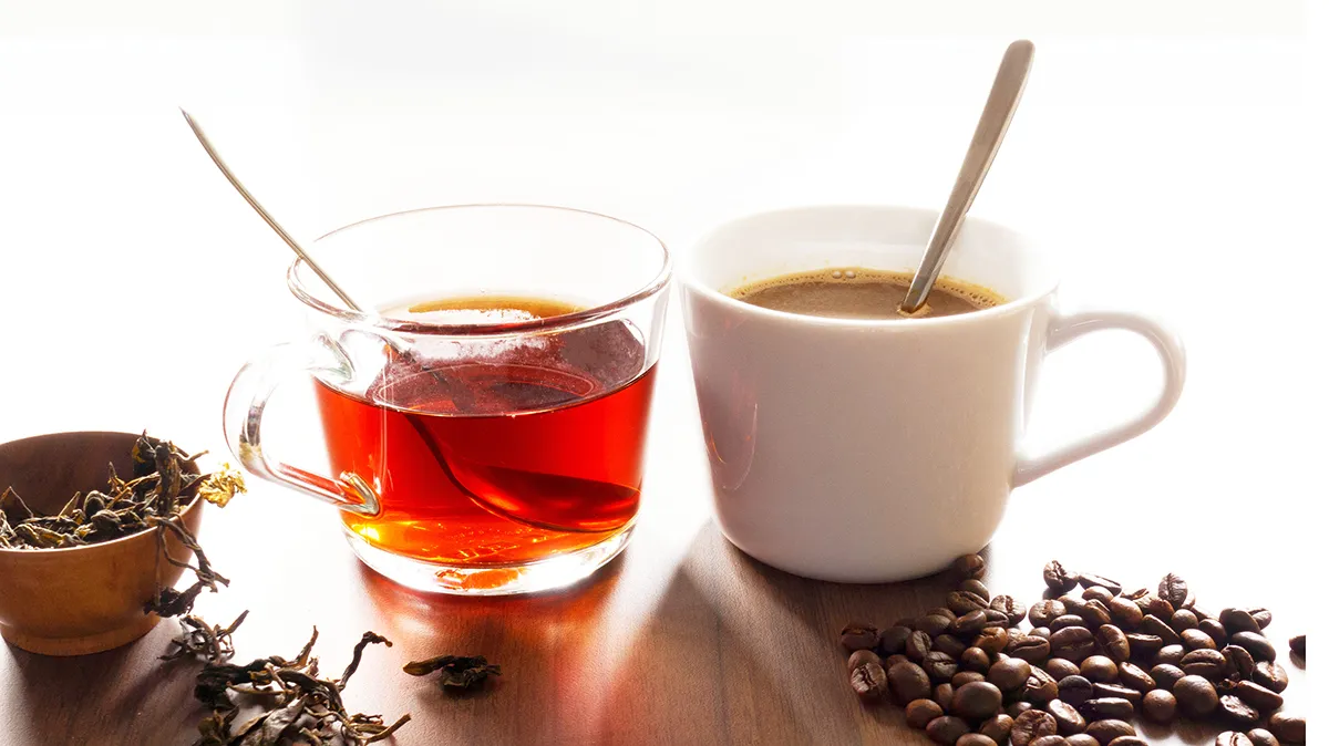 Zwei Tassen mit Kaffee und Tee auf einem Tisch.
