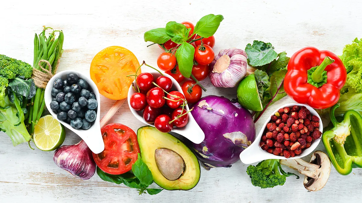 Bunte Auswahl an Obst und Gemüse auf hellem Tisch.