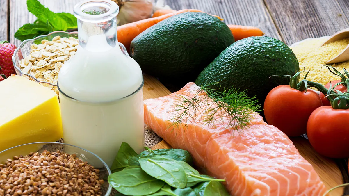 Lachs, Avocado, Milch und Gemüse auf Holztisch arrangiert.