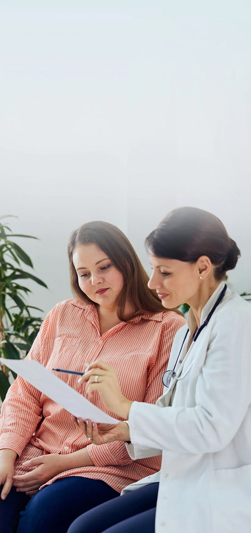 Ärtzin steht neben Patientin mit einem Zettel in der Hand