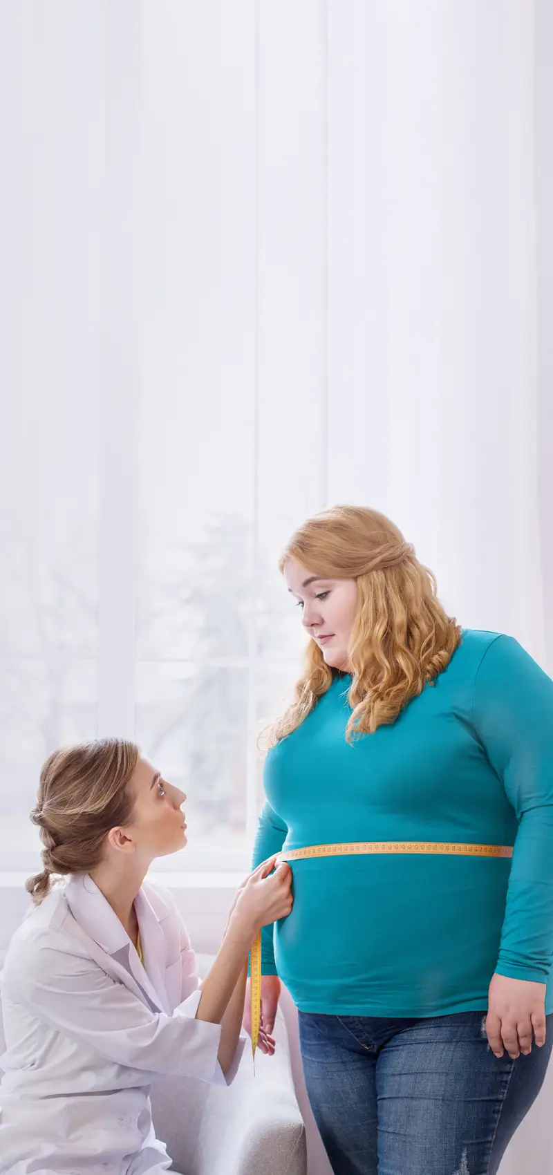 Ärztin misst den Taillenumfang einer Patientin in einer Praxis.