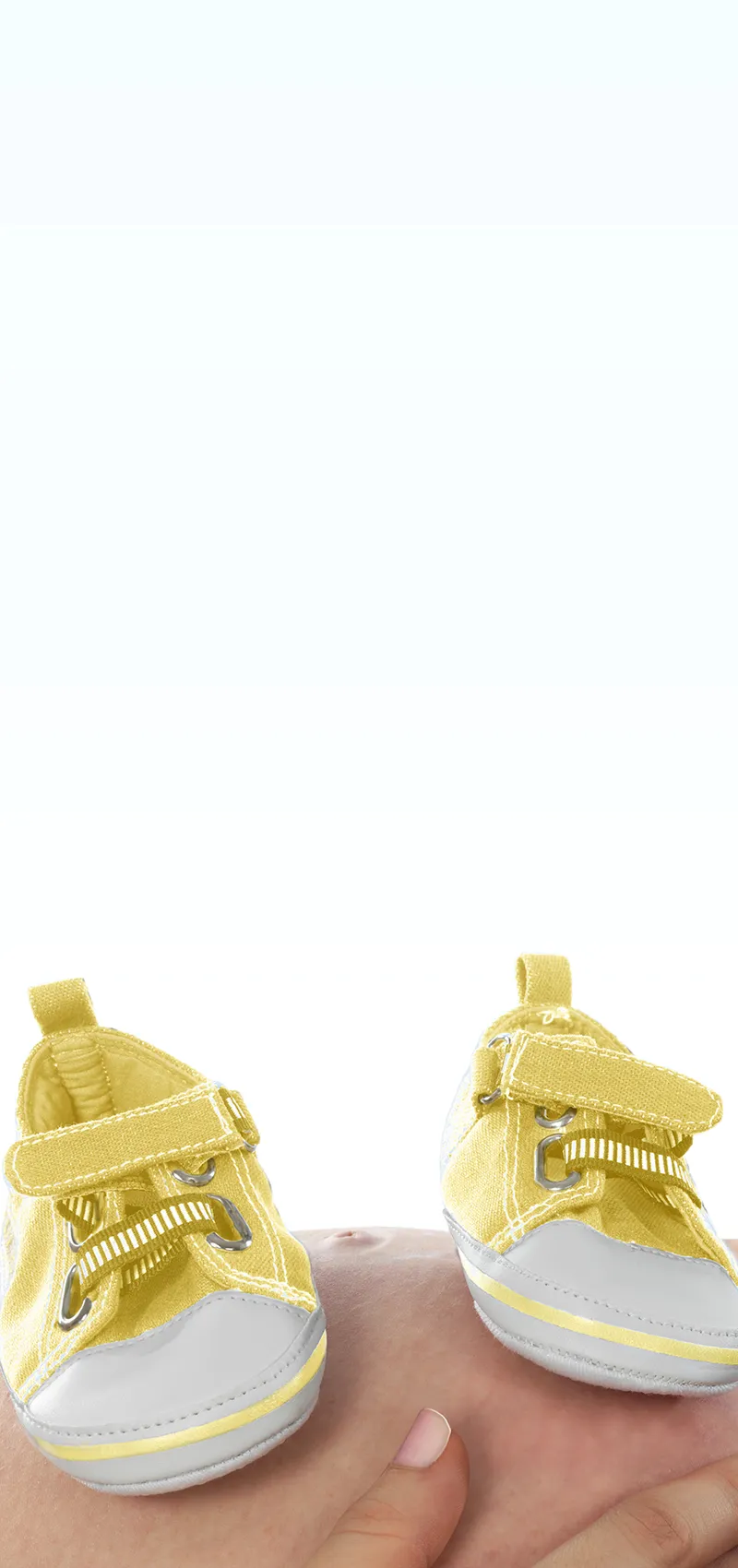 Gelbe Babyschuhe stehen auf einem schwangeren Bauch.