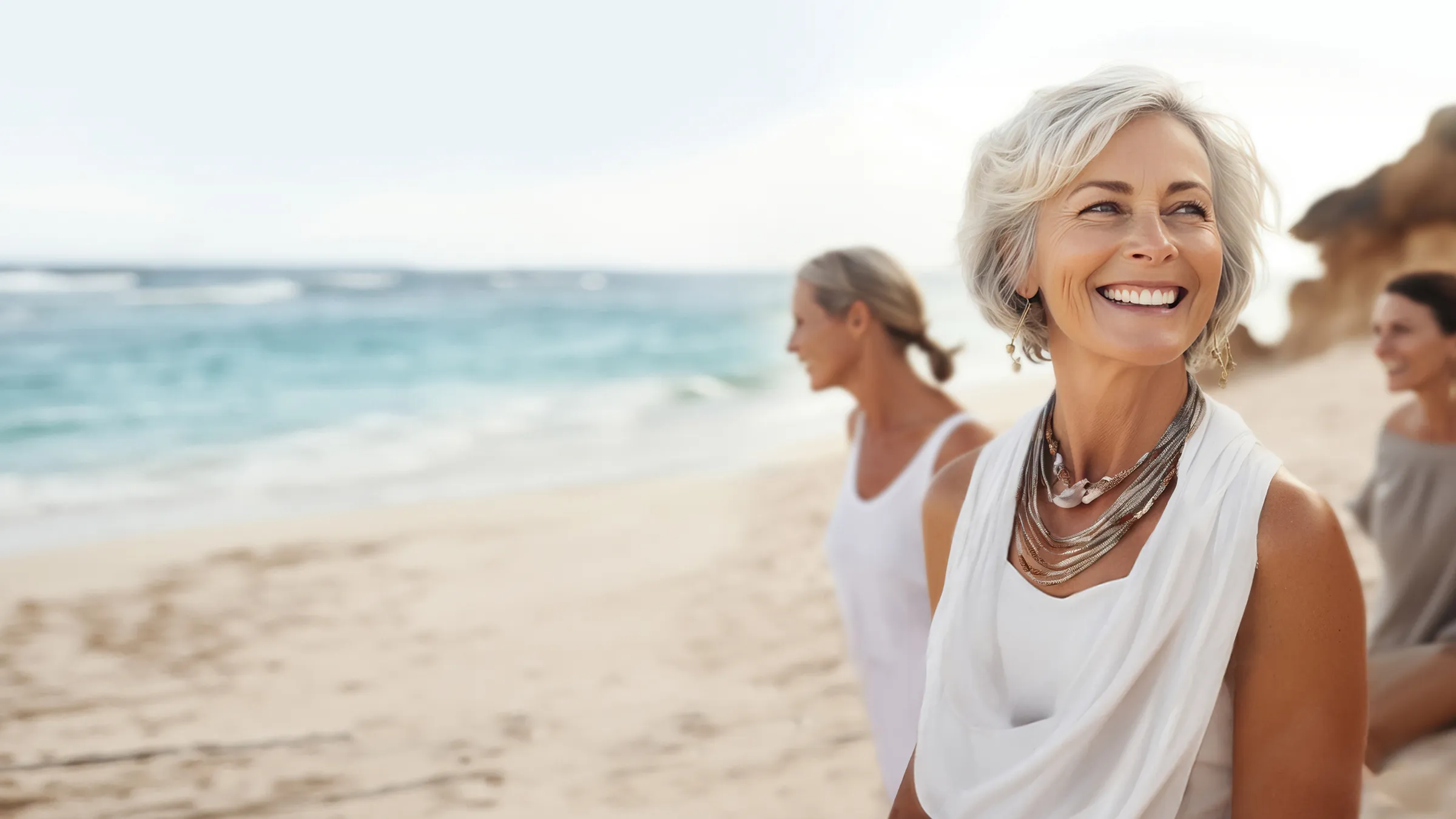 Lächelnde Frauen gehen am Strand entlang und genießen den Tag.