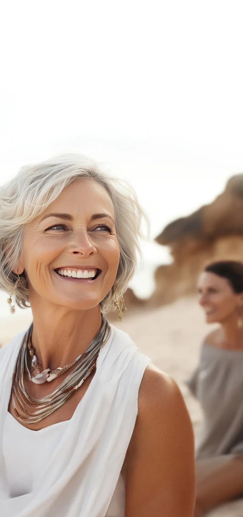 Lächelnde Frauen gehen am Strand entlang und genießen den Tag.