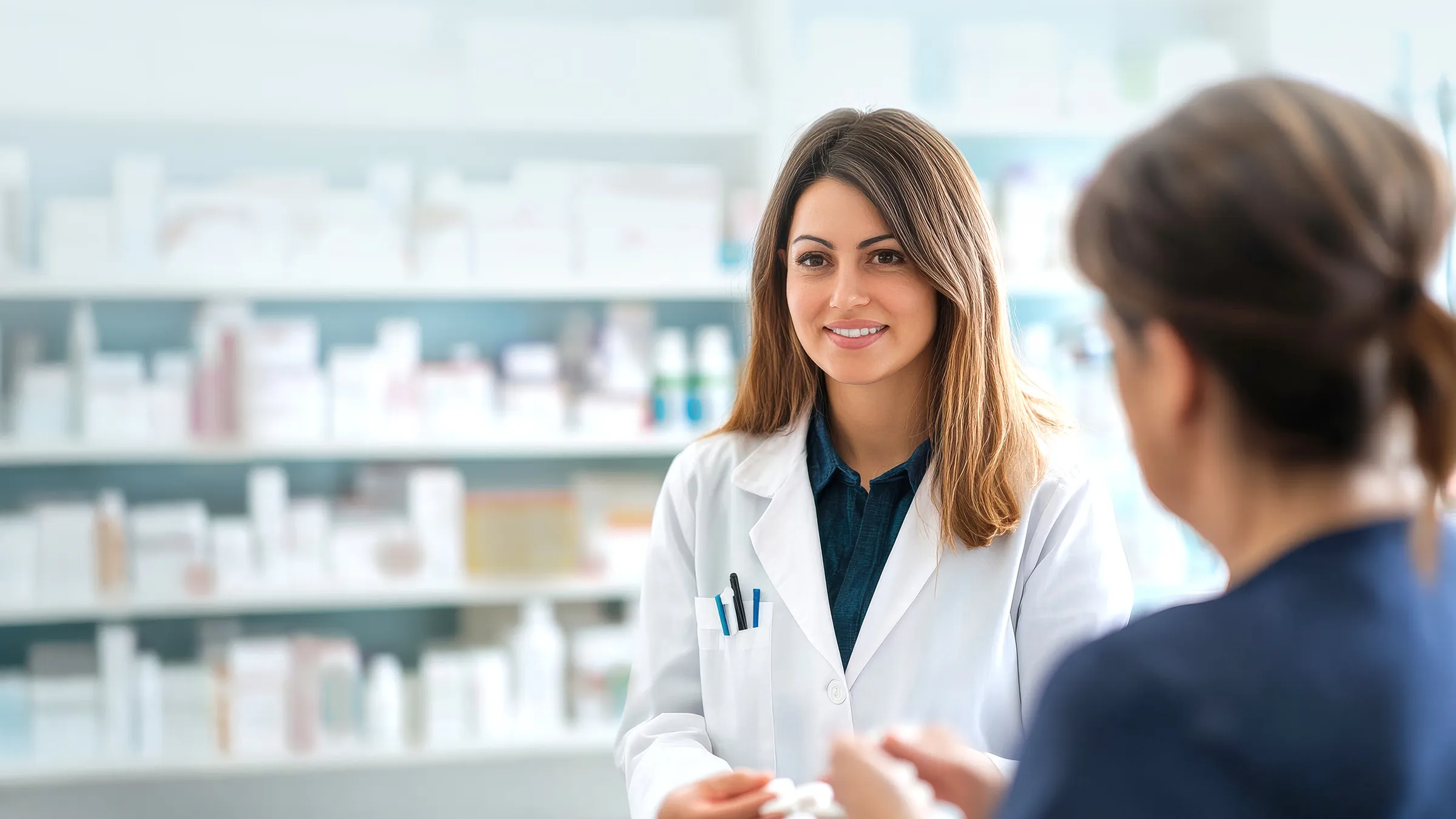 Apothekerin berät Kundin vor Medikamentenregal in Apotheke.