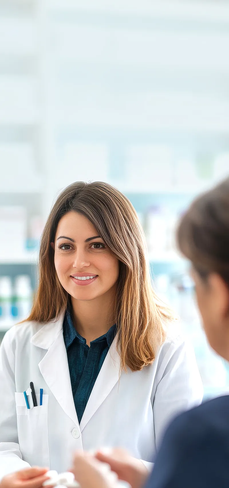 Apothekerin berät Kundin vor Medikamentenregal in Apotheke.