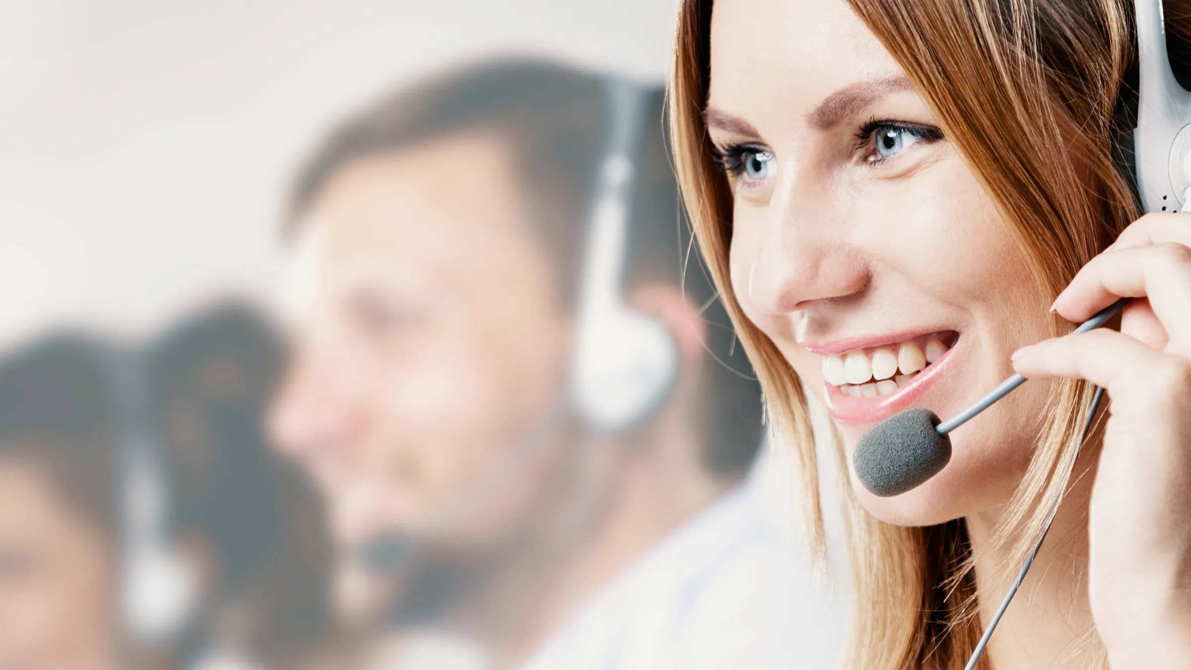 Lächelnde Kundendienstmitarbeiterin mit Headset im Callcenter.