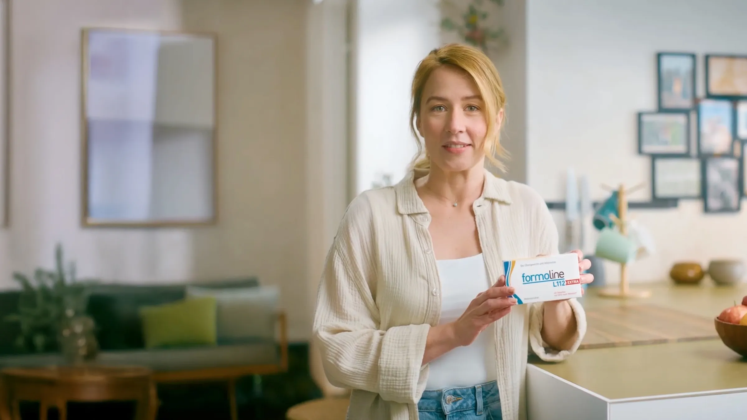 Frau hält formoline L112 EXTRA Packung in heller Küche, Szene aus TV-Spot.