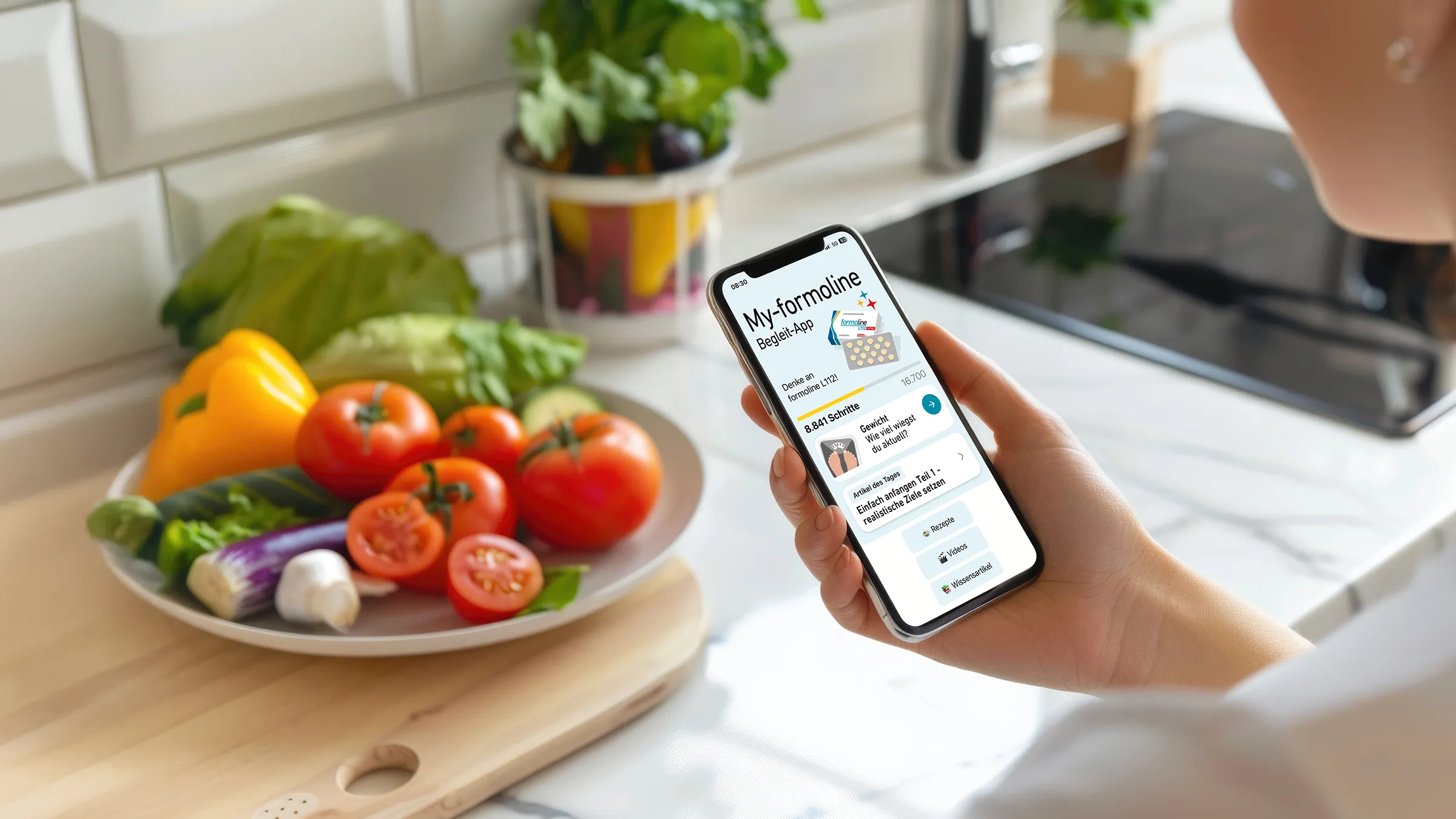 Smartphone mit My-formoline App neben frischem Gemüse in Küche.