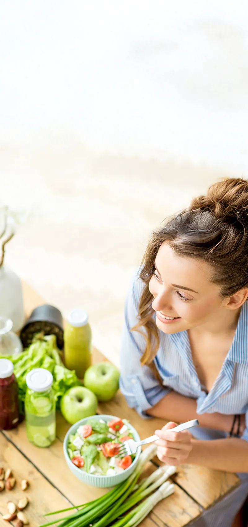 Frau isst gesunden Salat und umgeben von frischen Lebensmitteln.