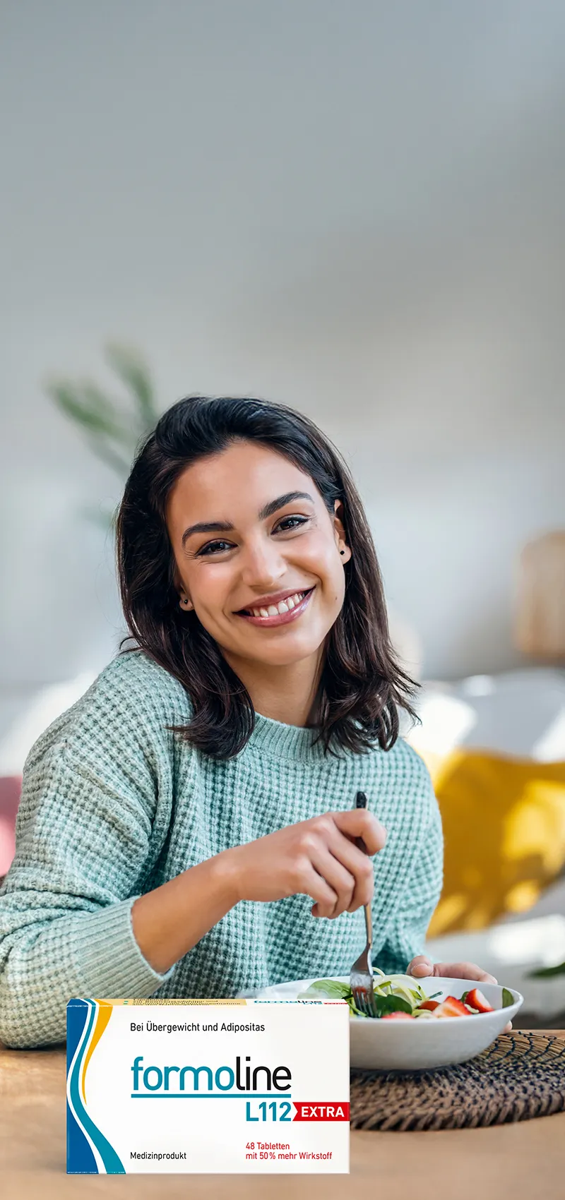 Frau isst gesunden Salat mit formoline L112 EXTRA Packung auf dem Tisch.