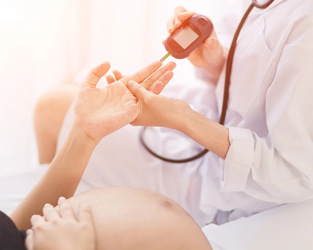 Arzt misst Blutzucker bei einer schwangeren Frau.