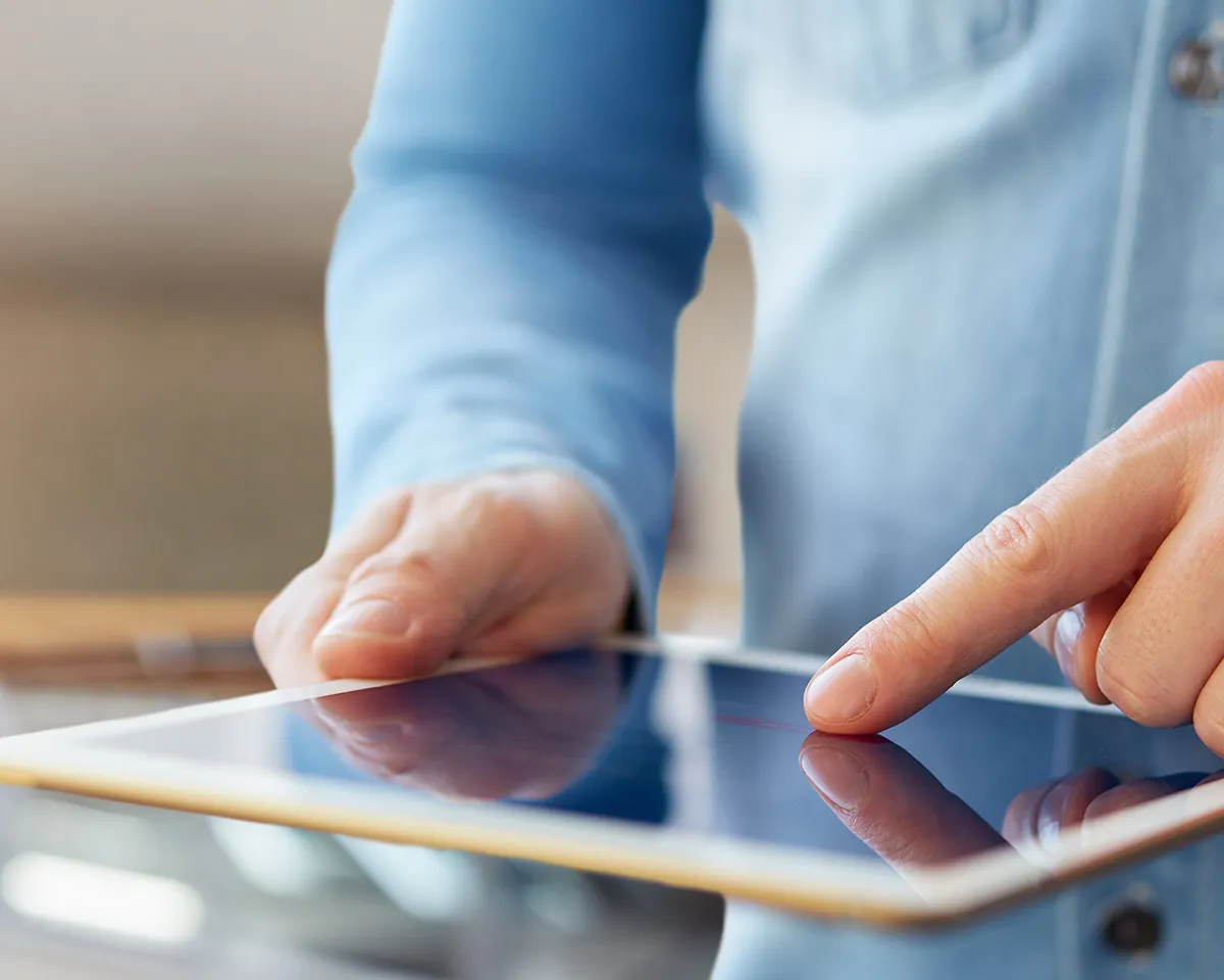 Person bedient Tablet mit Zeigefinger in Nahaufnahme.