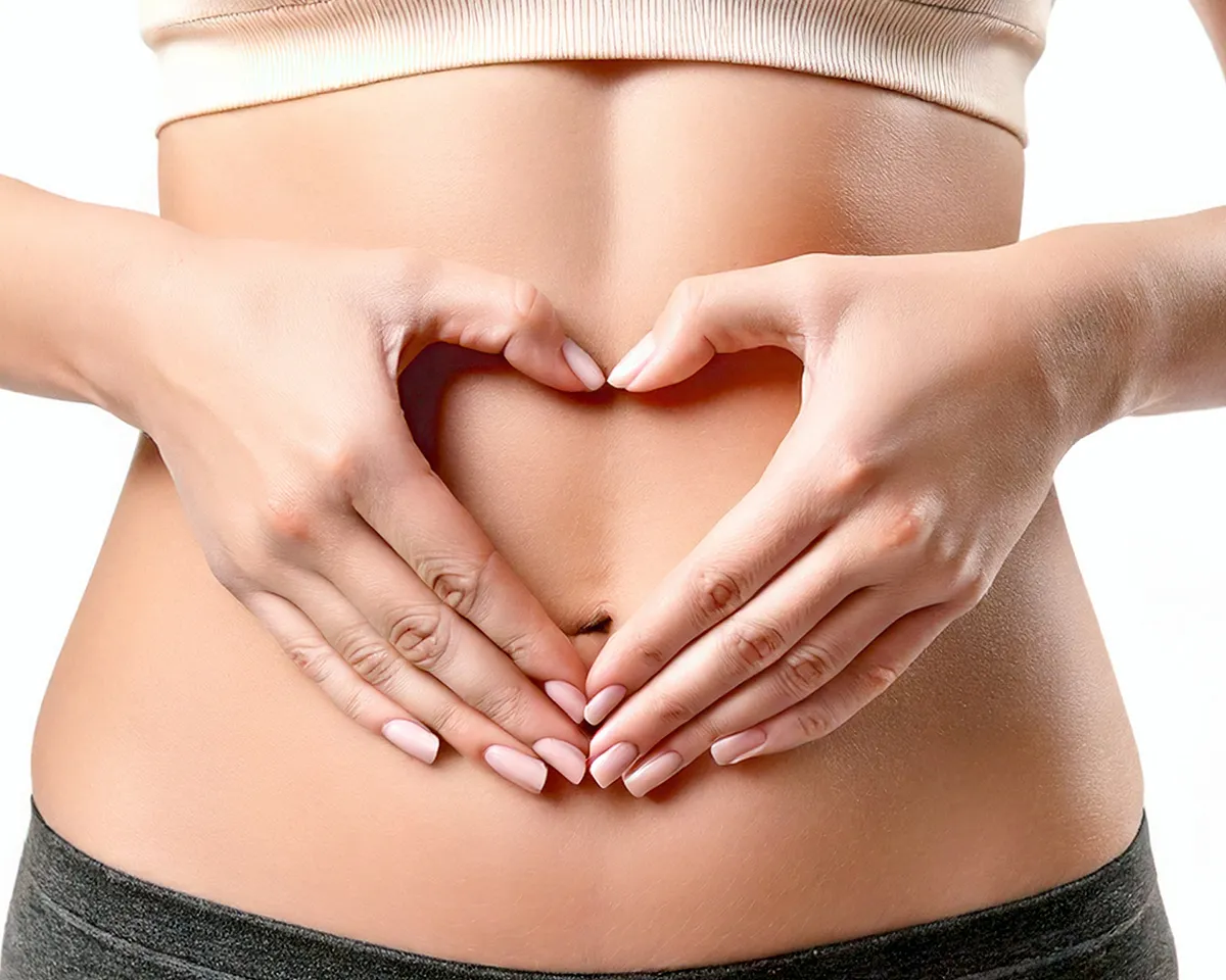 Hände formen Herz auf Bauch als Symbol für Wohlbefinden.